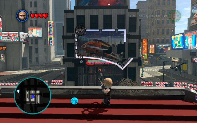 At the beginning of the stage approach to the balustrade as Hawkeye and detonate all silver elements surrounding a billboard at the opposite side of the huge hole - Times Square / Oscorp - Walkthrough - LEGO Marvel Super Heroes - Game Guide and Walkthrough
