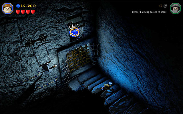 You need to hit the blue object above the gate, with the magic projectile - Stage 13 (Looking for Proof): Angmars Tomb - Walkthrough - LEGO The Hobbit - Game Guide and Walkthrough