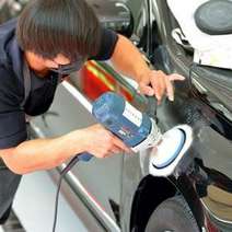 Car mechanic waxing a car