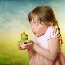 Small girl kissing a frog
