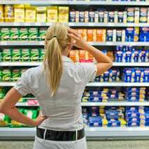 Woman deciding over shelf of products in supermarket