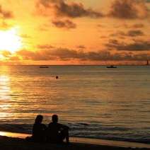 Couple watching a sun set by the sea