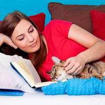  Woman reading a book with a cat lying by her side