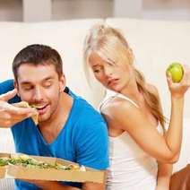  A man eating pizza and a woman holding an apple