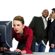  Woman looking to the computer with two whispering men behind her