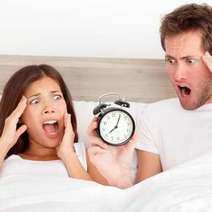 A couple holding an alarm clock, making shocked face 