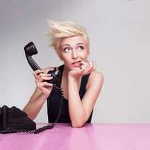  Blonde woman holding a black desk phone