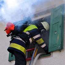  A fireman on a ladder at the window with smoke coming out