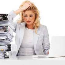 Woman at the computer with pile of folders 