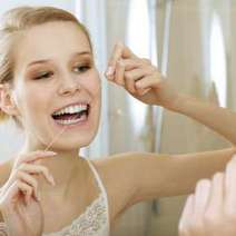  Woman cleaning her teeth with a dental floss