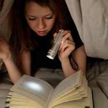  A girl reading a book with a flashlight