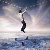  A man hanging on a rope with sharks beneath