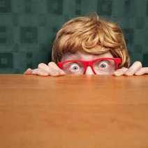  Boy wearing red glasses hidden behind a table