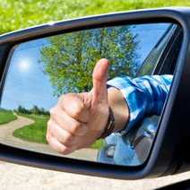  A man showing thumbs up in a rearview mirror