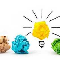 A picture of a light bulb made of yellow paper among other colourful papers 