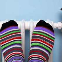  Feet in striped colourful socks getting warm by the radiator
