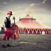 A guy with a violin in front of a circus tent