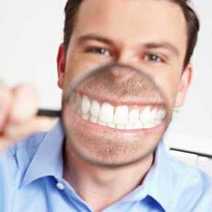 A guy showing his teeth through a magnifying glass