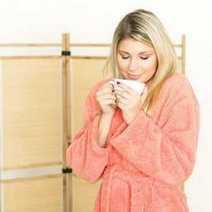  A woman in a dressing gown drinking coffee