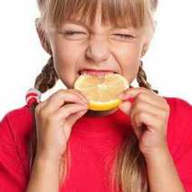  A girl biting a sour lemon