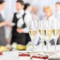 Row of filled champagne glasses with party in the background, 