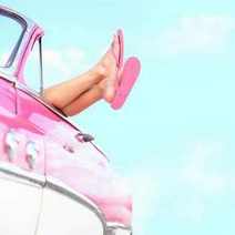 Feet in pink sandals stretched out from a pink cabrio