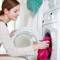 A women loading a washer with dirty clothes