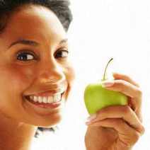 A young smiling woman holding a green apple
