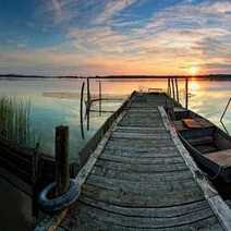 Sunset over a lake overlooking an old wooden pier with old boats